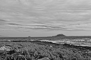 sea landscape with the ocean and a view of the Spanish island of De Lobos with a ship in the...