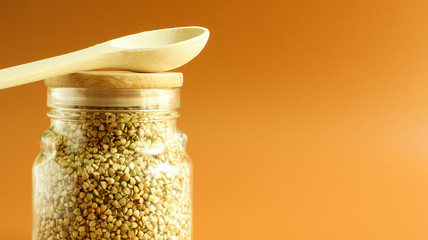 Green sprouts of raw organic buckwheat in a glass cereal jar with a wooden spoon. Vegan food...