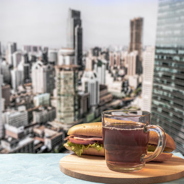 A cup of black coffee or tea and sandwich against the background of a blurry panorama of the city. Dream big concept. Life style, instagram