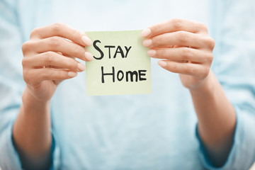 Woman holding adhesive note with Stay Home text