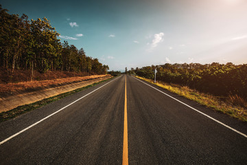 open road. Asphalt road through the green field and clouds on blue sky in summer day. 