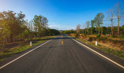 open road. Asphalt road through the green field and clouds on blue sky in summer day. 