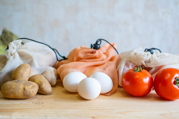  vegetables and eggs in eco friendly cotton bags on woofen table.