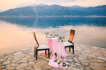Close-up of a wedding dinner table at reception. Romantic sunset dinner on beach. A table by the...