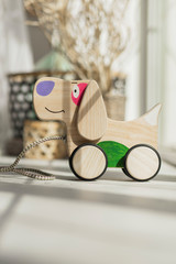 Photo of a wooden dog on wheels of beech on table.A toy for entertaining children and resting parents