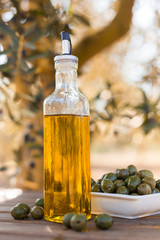 green olives and oil on table in olive grove