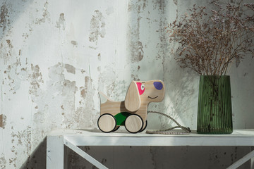 Photo of a wooden dog on wheels of beech on table.A toy for entertaining children and resting parents