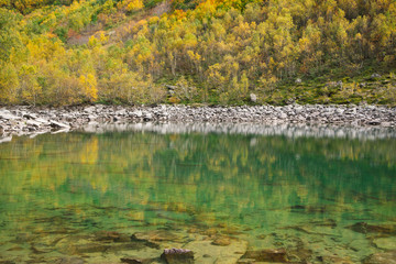Turquoise Baduk lake in mountains in Dombay national park, Caucasus, Russia. Beautiful autumn landscape.