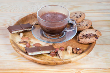 Hot chocolate among the nuts and confections on wooden dish