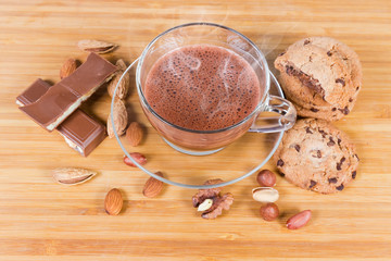 Hot chocolate among the nuts and confections on wooden surface