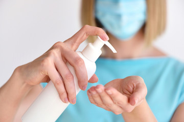 Young woman using antiseptic gel and wearing prevention mask, close up woman hands washing hands with sanitizer to avoid contaminating with Corona virus