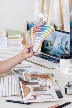Interior designer choosing color palette for new project and looking at printed photos of rooms