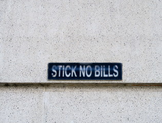 Inscription sur mur gris : Stick no Bills.