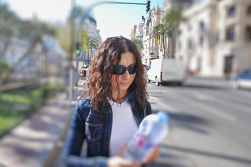 Happy female tourist visits city in spring holding a bottle of water