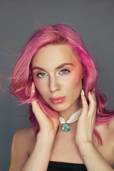Naklejka premium Beauty portrait woman with pink hair, creative vivid coloring. Bright colored highlights and shadows color on the face, a girl with jewelry. Dyed hair in the wind