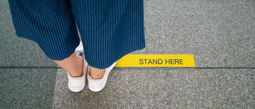 Banner photo of Asian woman standing on social distancing sign for keep distance and queue for entrance subway train a new normal life trend. corona virus, social distancing or new normal concepts