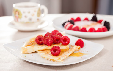 breakfast of pancakes with fresh raspberries on table
