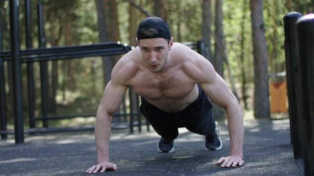 Adult caucasian sportsman is doing push up exercise topless at the gym at the park during his workout