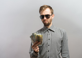 a young man  isolated over a gray background holding banknotes