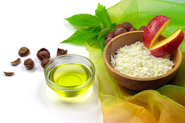 Hazelnut oil, hazelnuts, cottage cheese with slices of apple in wooden bowl isolated on white background