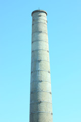 Old white brick tower against the clear blue sky background. Belfry for telecommunications. High pipe boiler house. Sunny day calm weather. Backdrop for mobile desktop vertical orientation.