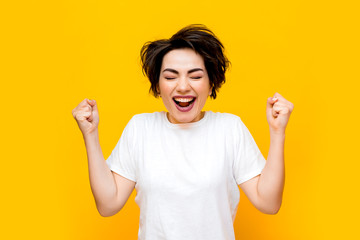 Young happy brunette woman with a short haircut in a white T-shirt on a yellow background. portrait of a young woman with various emotions on a yellow background. space for text