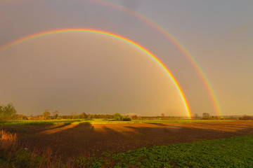 Rainbow over stormy sky. Rural landscape with rainbow over dark stormy sky in a countryside at summer day.