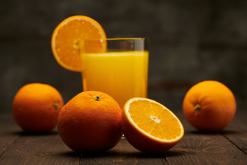 Fresh orange juice and fruits whole and sliced on a wooden table - natural and healthy food and drink. One glass of cocktail with a slice of fruit