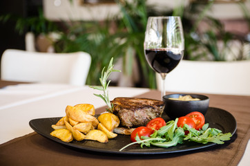 Freshly made pork steak with vegetables and glass of red wine