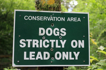 A warning sign in a forest to keep dogs on leads