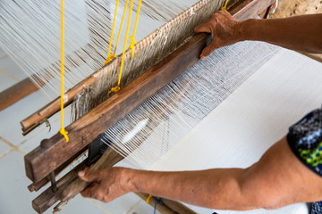 blur motion hand slide a loom machine for made cotton or silk weaving , occupation of villagers at workplace in rural . ancient from asian Thai culture made a clothes .