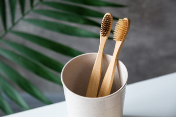 Eco friendly bamboo toothbrushes in glass on bathroom table. Natural wooden toothbrushes for dental care, personal hygiene. Zero waste, plastic free, sustainable lifestyle concept