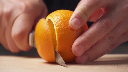 Slicing an orange fruit on a kitchen cutting Board, wooden table as background, close view. - Powered by Adobe