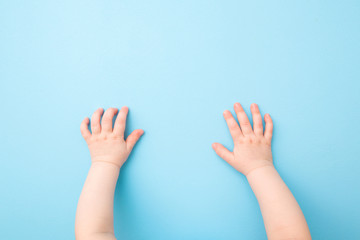 Baby hands on light blue table background. Pastel color. Closeup. Point of view shot. Top view.