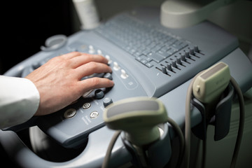 Close up shot of technician operating an ultrasound machine at a clinic. 