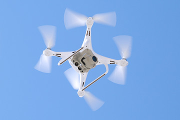 White drone with camera against blue sky