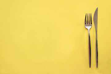 A fork and a knife on yellow background.