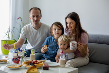 Happy family, having pancakes for breakfast, eating in living room, talking and lauging