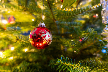 Red christmas ornament in a tree with lights