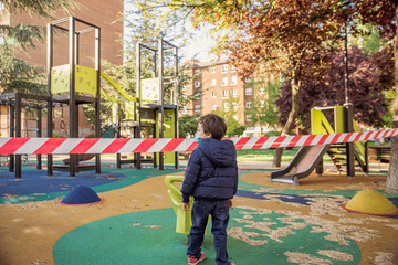 healthy little kids with face mask during coronavirus covid 19 pandemic lockdown ending with playgrounds closed with police tape