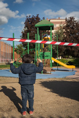 healthy little kids with face mask during coronavirus covid 19 pandemic lockdown ending with playgrounds closed with police tape