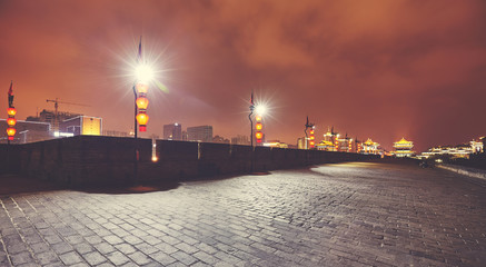 Fototapeta na wymiar Panoramic view of illuminated Xian city wall at night, color toning applied, China.