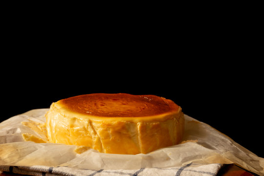 Whole Basque burnt cheesecake isolated on wooden table.