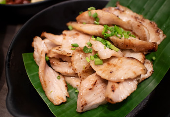 Charcoal-boiled pork neck, serving on banana leaf and black ceramic plate. Ready to eat in restaurant. North-east Thai traditional food