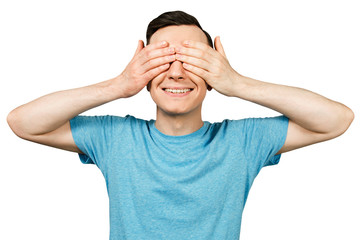 Young smile guy dressed in a blue t shirt, close his eyes with hands on a isolated white background.