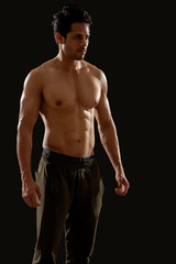 Fototapeta na wymiar Man standing and showing his muscles in front of a dark background. 
