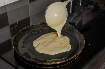 Pancakes are fried in a pan on an induction stove