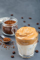 Trendy korean drink Dalgona coffee with ice, dark gray background, vertical, copy space