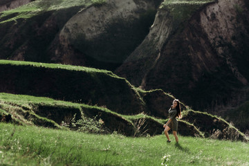 young beautiful girl runs on the green hills of the mountains