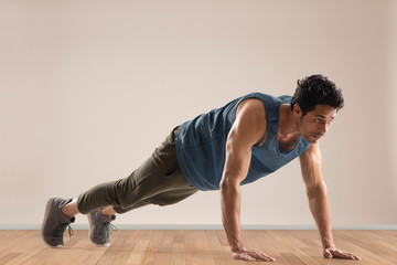 Man doing push ups over a plain background. 
